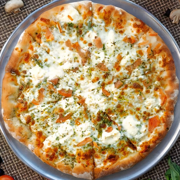 A white pizza with pesto, ricotta cheese, and sun-dried tomatoes on a metal tray.